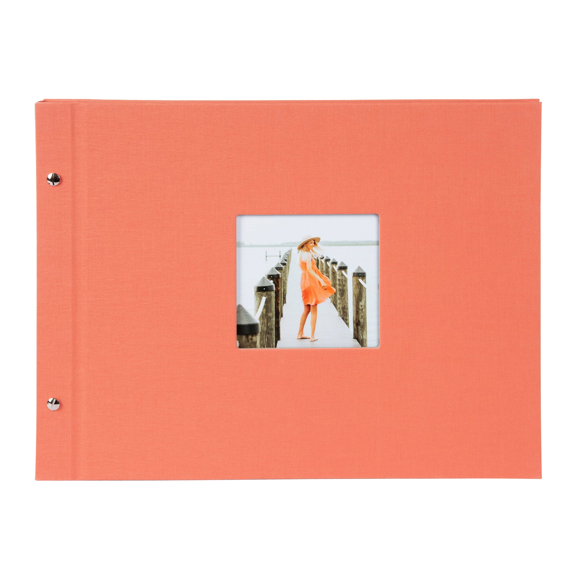 A coral Goldbuch photo album with a woman walking on a deck, showcasing a serene waterfront scene.