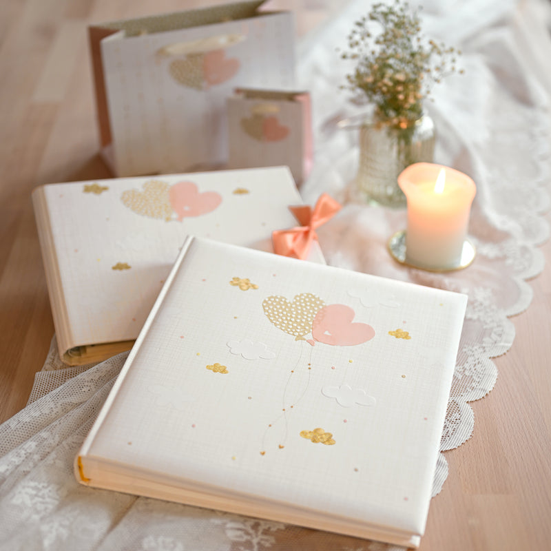 A Goldbuch white photo album with heart shaped balloon design, decorated with golden clouds, ideal for your treasured moments.