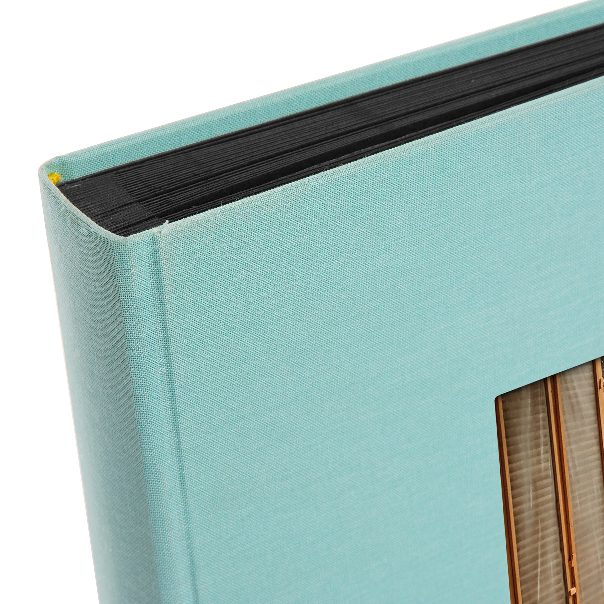 A Goldbuch aqua blue photo album with a cover illustration of a beach house, showcasing its hardcover design and black pages.