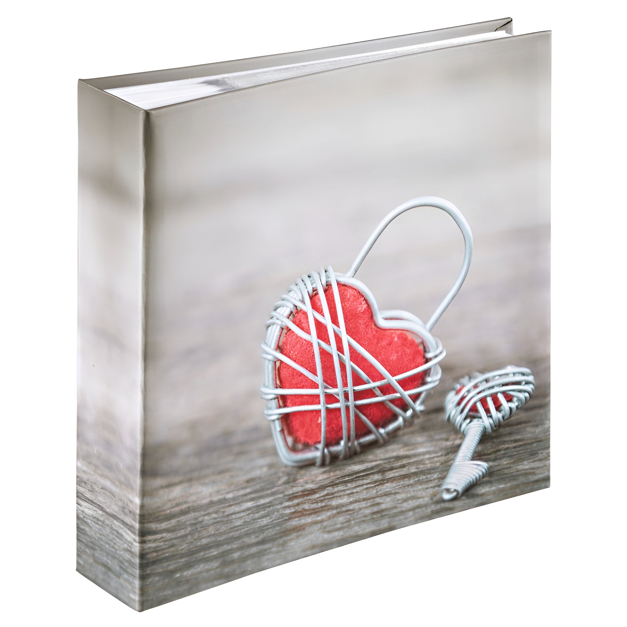 A red heart-shaped key and a wire heart-shaped lock resting on a Hama photo album, representing love and memories.