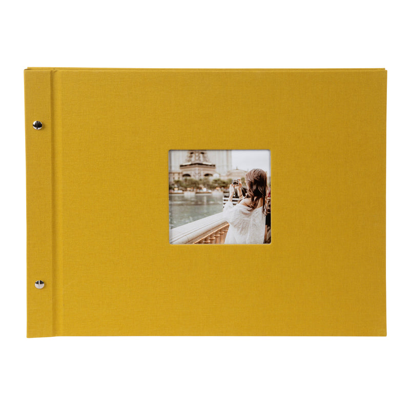 A Goldbuch mustard photo album with a cover illustration of a woman taking photos, showcasing its hardcover design and black pages.