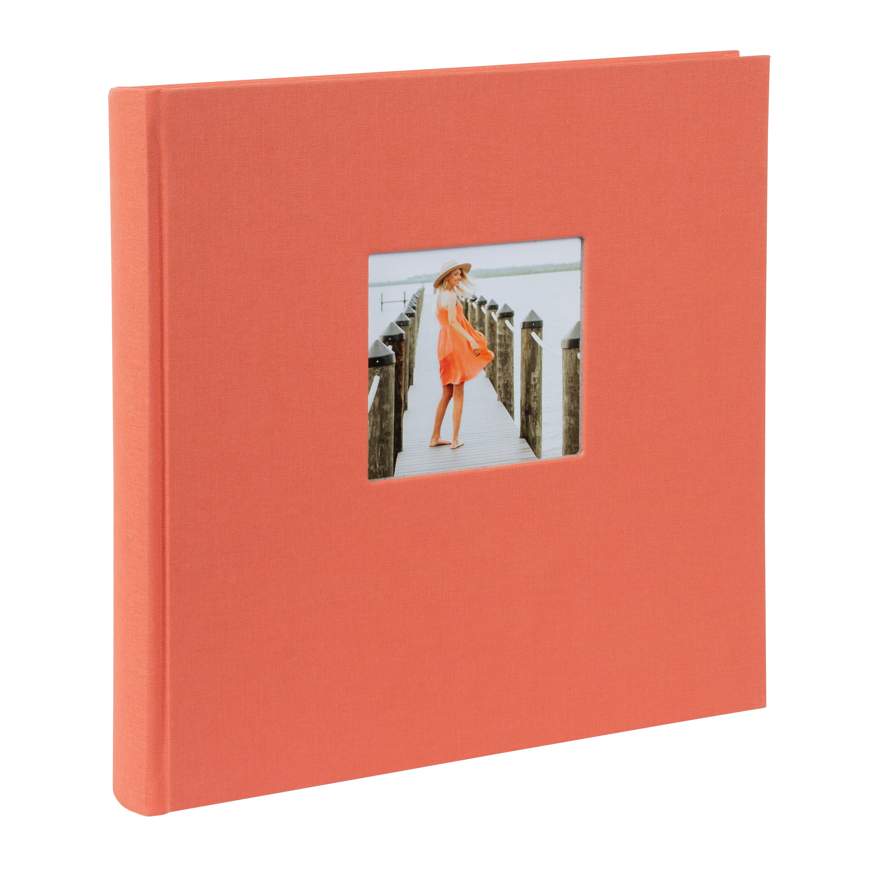 A Goldbuch salmon coloured photo album with a cover illustration of a woman on a pier showcasing its hardcover design and black pages.