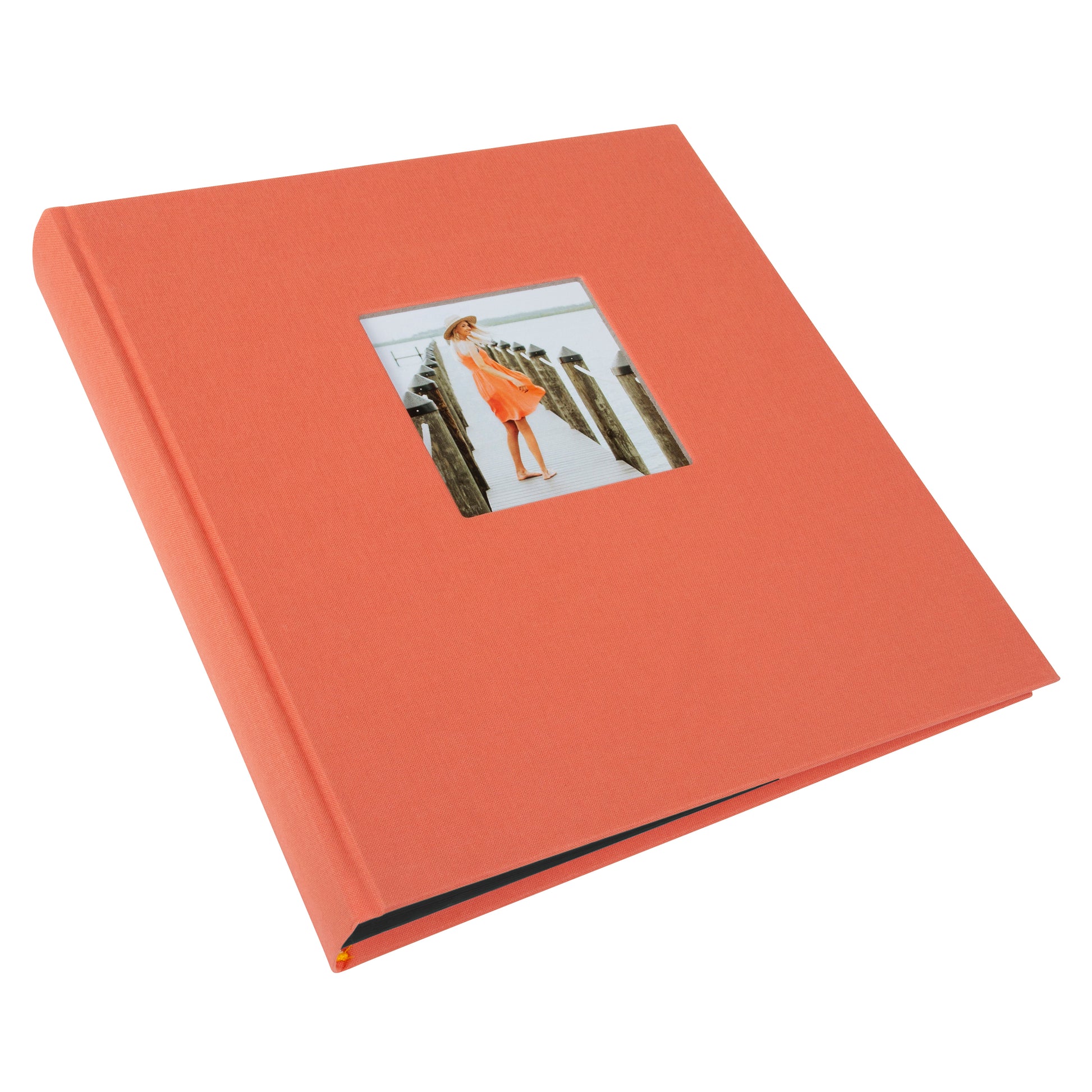 A Goldbuch salmon coloured photo album with a cover illustration of a woman on a pier showcasing its hardcover design and black pages.