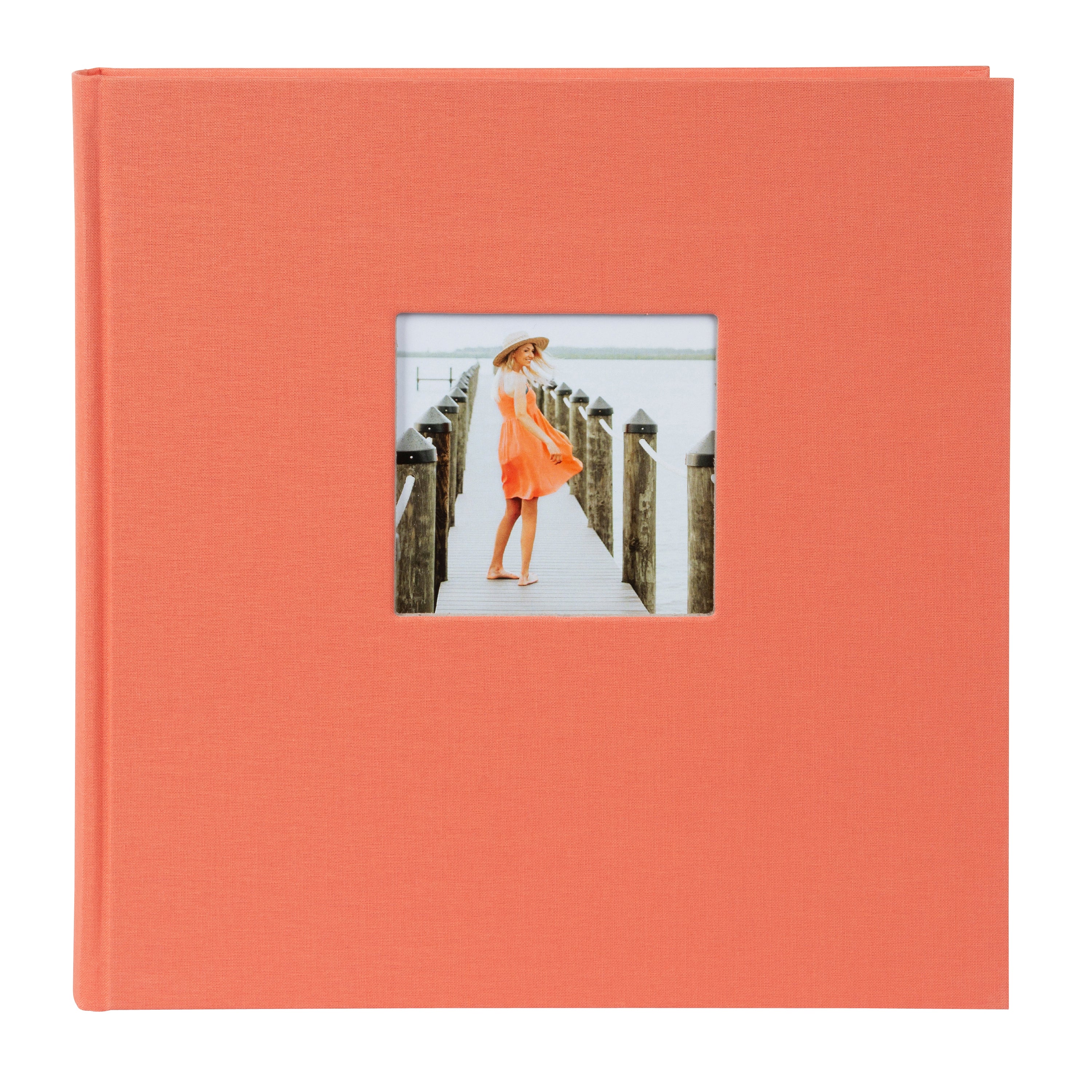 A Goldbuch salmon coloured photo album with a cover illustration of a woman on a pier showcasing its hardcover design and black pages.