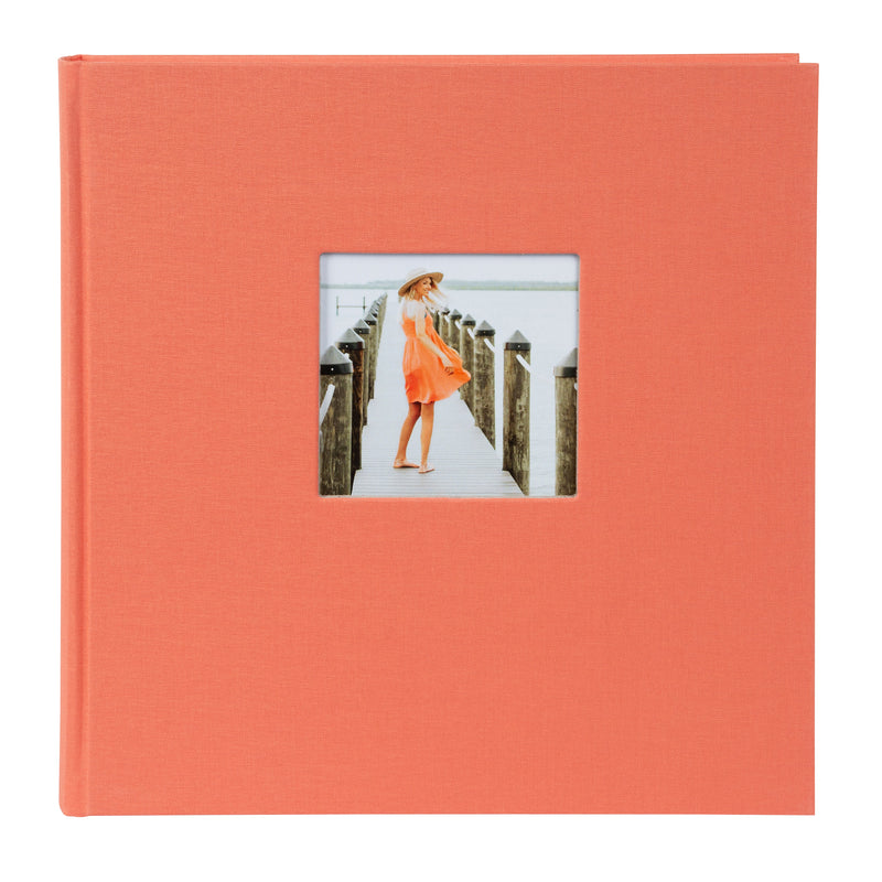 A Goldbuch salmon coloured photo album with a cover illustration of a woman on a pier showcasing its hardcover design and black pages.
