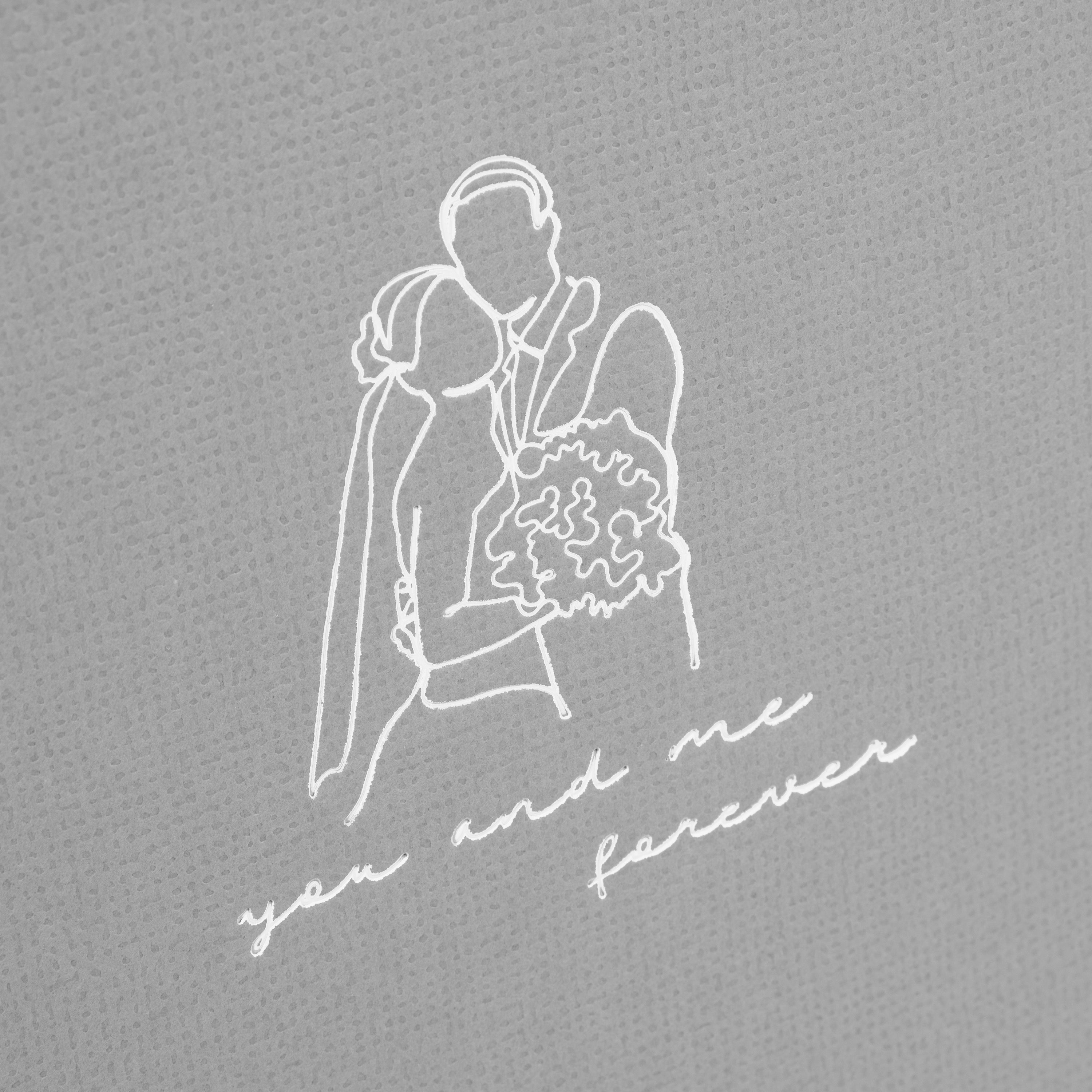 A grey Goldbuch photo album with an illustration of a man and a woman on its front cover.