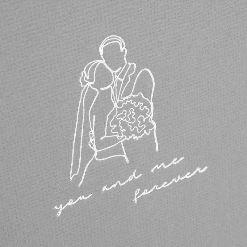 A grey Goldbuch photo album with an illustration of a man and a woman on its front cover.