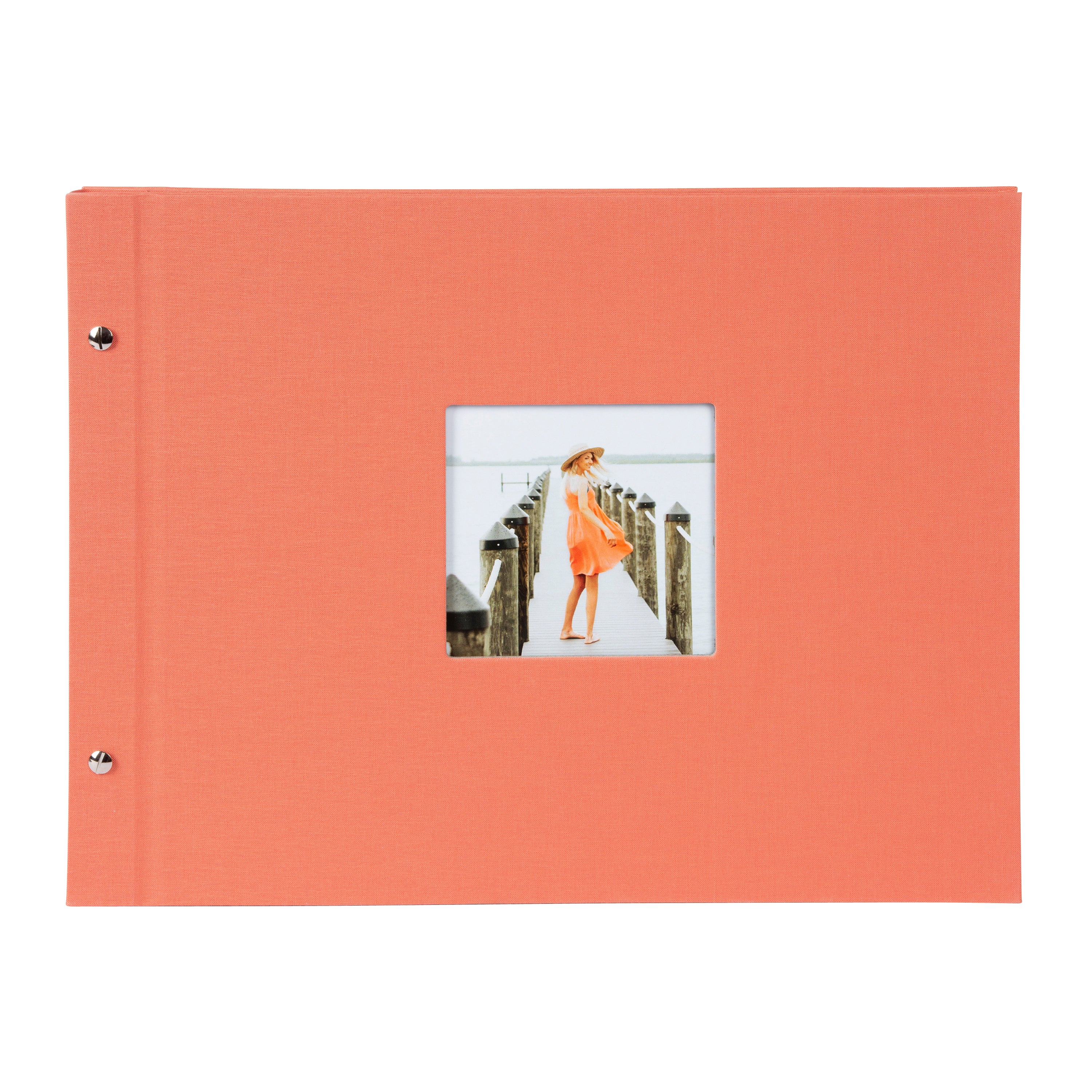 A coral Goldbuch photo album with a woman walking on a deck, showcasing a serene waterfront scene.
